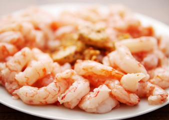 Shrimps on a white plate with herb and chilli butter.