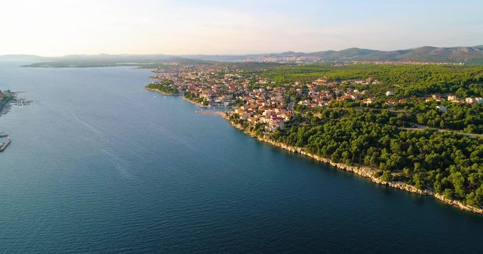 Village on croatian coast, C4k aerial, drone shot, towards the Brodarica town, on the mediterranean shore and the adriatic sea, near Sibenik, on a sunny, summer evening, in Croatia