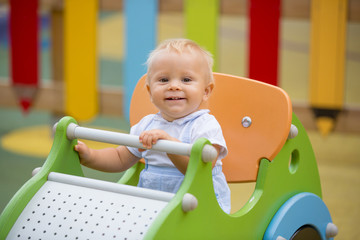 Adorable baby boy, playing with different rides on the playgdorund