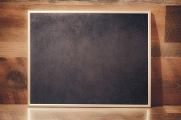 Chalkboard with golden frame in front of wooden background