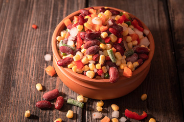 Homemade mixture of frozen vegetables: carrot, paprika, beans, green beans, onion and corn. Old wooden table.