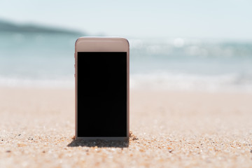 Smart phone on sand beach texture background.