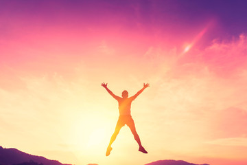 Happy man jumping at top of mountain with sunset sky abstract background.