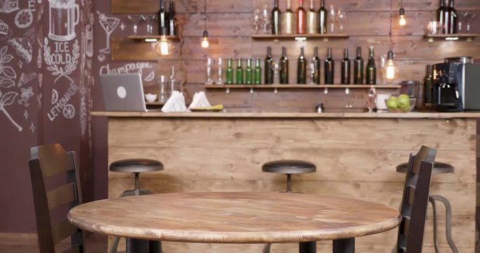 Parallax shot of an empty table and two chairs in front of a bar. A small, vintage coffee shop. Wood old stylish decor.