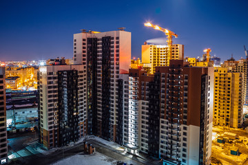 Fototapeta na wymiar Construction of modern high multistory residential buildings, night aerial view of building yard