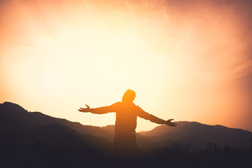 Copy space of man rise hand up on top of mountain and sunset sky abstract background.