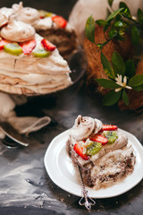ropical aquafaba cake with kiwi, strawberry and coconut cream on dark table with ingredients and flowers