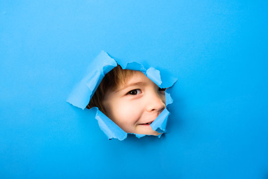 Through paper. Kid looking through paper. Spy eye watching through a hole. Child's eye looking through hole. Boy breaks paper. Eye. Sale. Advertising. Discount.
