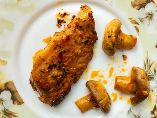 Top view on a plate with fried juicy pork and three half of champignon