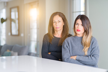 Beautiful family of mother and daughter together at home skeptic and nervous, disapproving expression on face with crossed arms. Negative person.