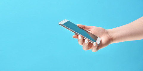 Girl hand holding modern smartphone on blue background