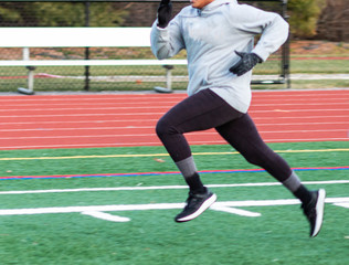 Runner sprinting on a green turf field in the winter
