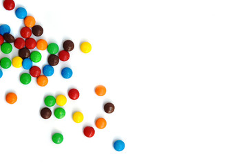 A scattering of colored small chocolates on a white background.Small colored candies