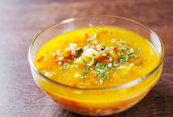 chicken soup with vegetables and rice in glass Bowl on wooden table background