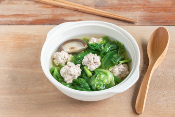 lettuce clear soup with pork balls in a ceramic bowl on wooden table, close up. asian homemade style food concept.