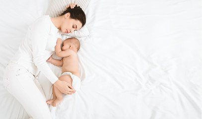 Young mom and her cute baby sleeping in bed