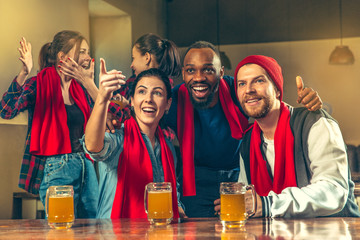 Sport, people, leisure, friendship, entertainment concept - happy male and female football fans or good young friends drinking beer, celebrating victory at bar or pub. Human positive emotions concept