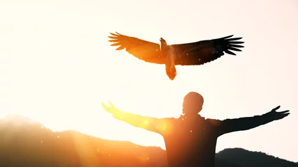 Fototapeten Mann hebt die Hand auf Berg- und Sonnenuntergangshimmel mit abstraktem Hintergrund der Adlervogelfliege. © tonktiti
