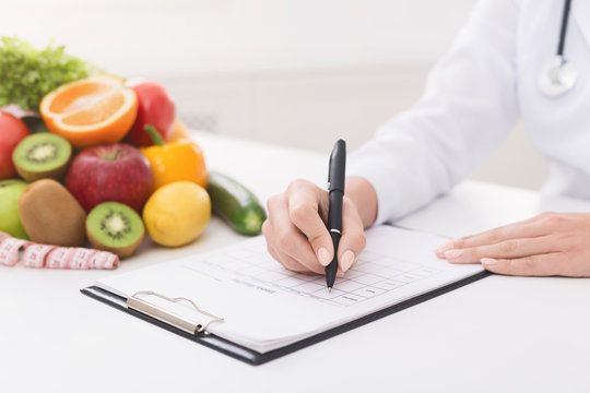 Female nutritionist doctor writing vegetable diet plan