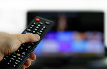 Hand holding remote control: Binge watching TV show