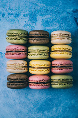 verschiedene Macarons hochkant aufgereiht und von oben fotografiert mit freiraum auf blauem...