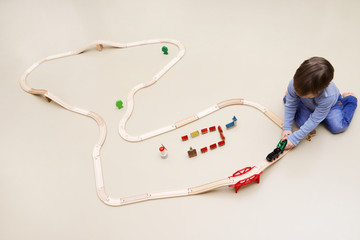 Ein kleiner Junge spielt mit einer Holzeisenbahn