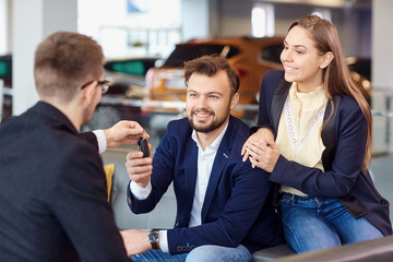 The dealer gives the keys to the new car to the customer