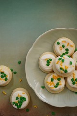St Patricks day frosted cookies with green clover leaf sprinkles, selective focus