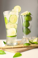 Green lemon juice with green lemon in glass on bamboo mat.Vertical.