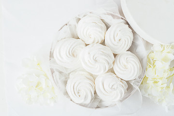 White tender marshmallow in a white box on a light background decoration flowers. Horizontal frame. View from above.