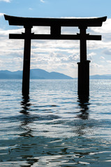 Close-up shot of the silhouette of the less-known "floating" torii gate of Shirahige Shrine in Lake Biwa near Shiga Prefecture's Takashima City in portrait view.