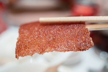 close up on barbecued suckling pig on a chopsticks