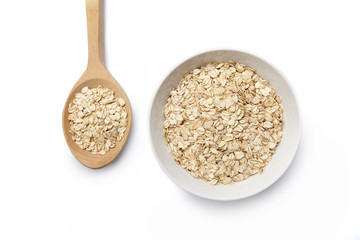 A bowl and wooden spoon with oat-flakes cut out. Top view.
