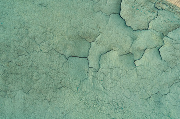 background of old dirty faded green paint cracked and partially peeled on the wall