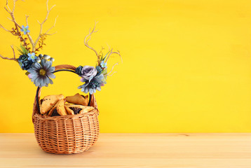 Purim celebration concept (jewish carnival holiday) with traditional hamantasch cookies and deer antlers floral decoration over wooden table