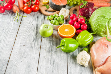 Trendy pegan diet - vegan plus paleo diet food concept, many fresh vegetables, fruits, raw beef and chicken meat, salmon fish, white wooden background top view copy space