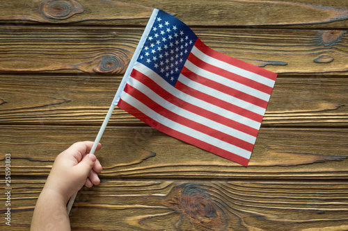 American flag in hand on wooden background. independence day holiday.