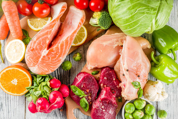 Trendy pegan diet - vegan plus paleo diet food concept, many fresh vegetables, fruits, raw beef and chicken meat, salmon fish, white wooden background top view copy space