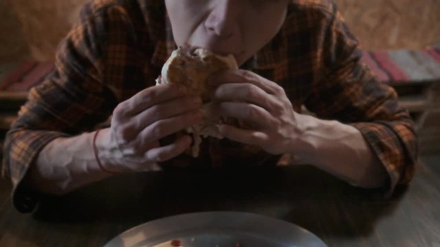 A stern bearded man aggressively and rudely eats sandwiches. Eats fast food. The concept of obesity society and poor nutrition.