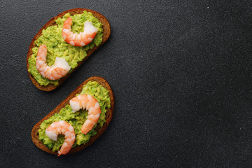 shrimp and guacamole with bread on dark background