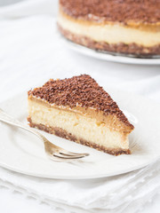 Slice of vegan millet cheesecake with date caramel on a clear background.