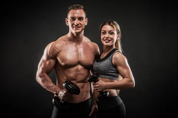 Gordijnen Sporty young couple posing on black background © Maksim Toome
