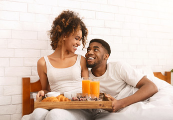 Obraz na płótnie Canvas Happy black couple enjoying breakfast in bed