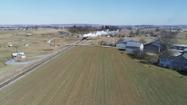 Aerial View of Amish Countryside With Steam Passrnger Train Puffing Through on a Winter Day as Seen by a Drone