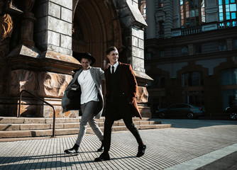Two fashion beautiful man models posing on city street. Wearing in classic and casual closes. Suit,...