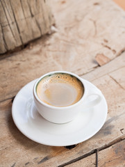 Double espresso in a white cup, on a rustic dhow wooden background.