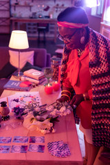 African american plump fortune-teller with a golden watch holding flowers