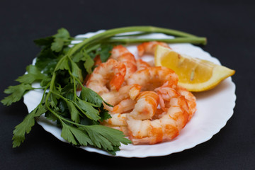 Shrimps, lemon and greens on a white plate