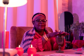 African american plump fortune-teller with a golden watch holding hands under the cup