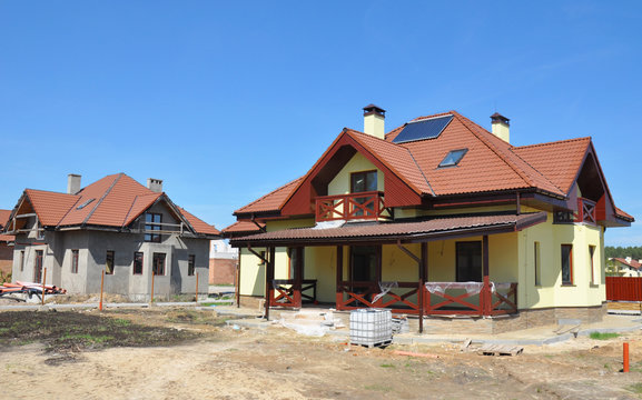 House under construction. House construction site with clay roof, lightning rod, solar water heater panels, attic skylight windows, roof lightning protection.